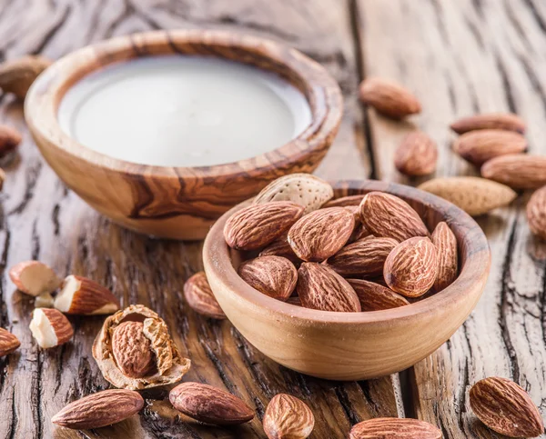 Almond nuts and milk on wooden table.