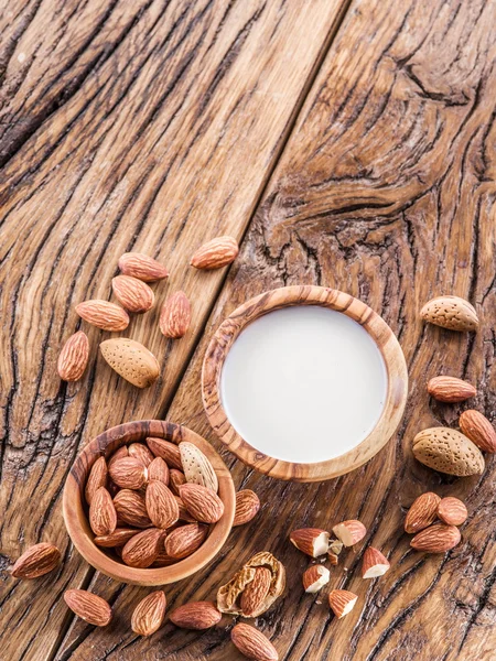 Nueces de almendra y leche sobre mesa de madera . — Foto de Stock