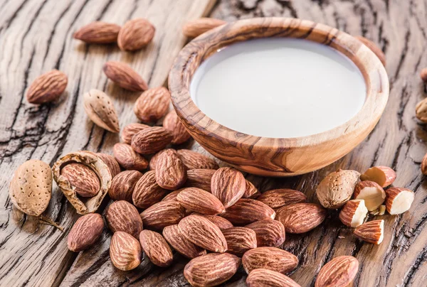 Mandelnüsse und Milch auf Holztisch. — Stockfoto