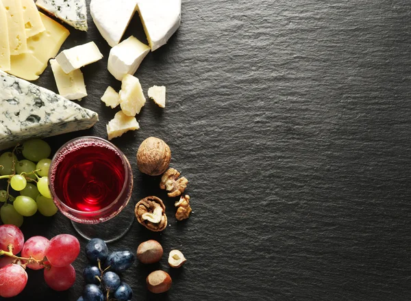 Olika typer av ostar med glas vin och frukt. — Stockfoto