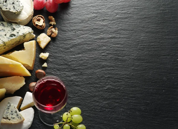 Different types of cheeses with wine glass and fruits. — Stock Photo, Image