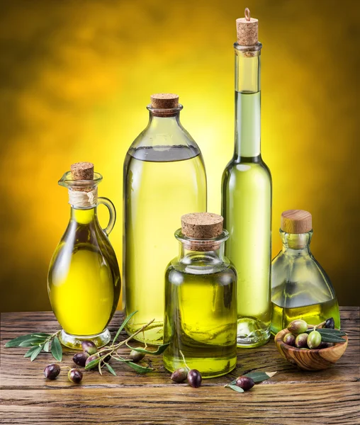 Botellas de vidrio de aceite de oliva y algunas bayas en la mesa de madera . —  Fotos de Stock