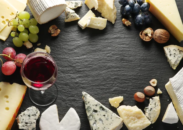 Verschiedene Käsesorten mit Weinglas und Früchten. — Stockfoto