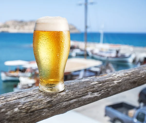 Copo de cerveja leve no balcão da barra à beira-mar.Barcos no doc — Fotografia de Stock