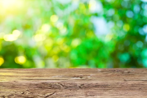 Holztisch und verschwommenes Laub auf dem Hintergrund. — Stockfoto