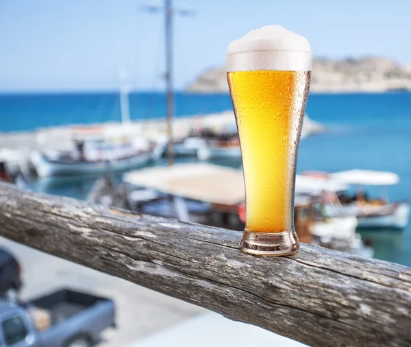 Copo de cerveja leve no balcão da barra à beira-mar.Barcos no doc — Fotografia de Stock