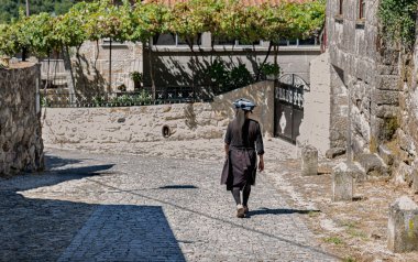 Portekiz 'de bir köyün kaldırımlı caddesinde yürüyen siyahlar giymiş köylü bir kadın.