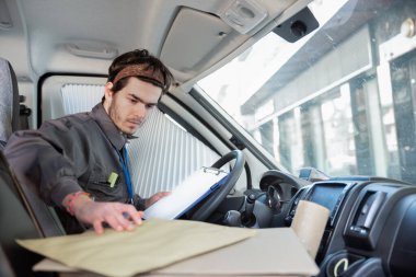 Minibüsteki kurye teslimat siparişlerini düzenliyor.