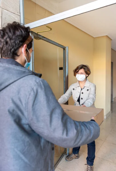 Pošťák Obličejovou Maskou Balíčkem Doručeným Ženě Maskou Dveřích Domu Udržujte — Stock fotografie