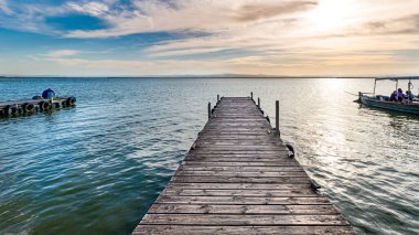 Ahşap iskelede gün batımı ya da tekne ve çiftle denizde iskele.