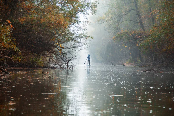 Sis dolu ağaçların altında, nehir kıyısındaki yemek masasında yüzen kürekçi, tanınmayan bir kadın.
