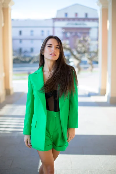 graceful caucasian female in a green suit and black blouse is walking in the shadow of arch of the ancient theater