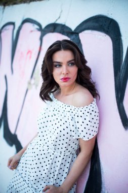 extravagant female with smeared makeup in white dress and red sneakers near a painted wall