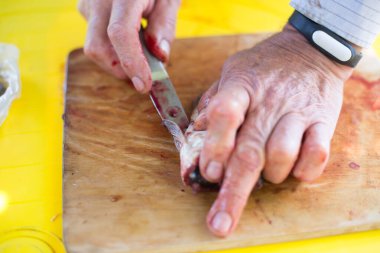 Adamın elleri teraziyi temizliyor ve bıçakla taze bir balığı kesiyor.
