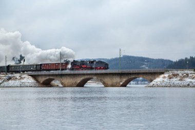 Köprüde kış gölü üzerinde klasik buhar lokomotifi