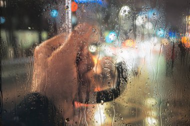 Pencereden yağmur damlalarıyla bak. Yağmurlu bir hava. Cama yağmur damlaları damlıyor.