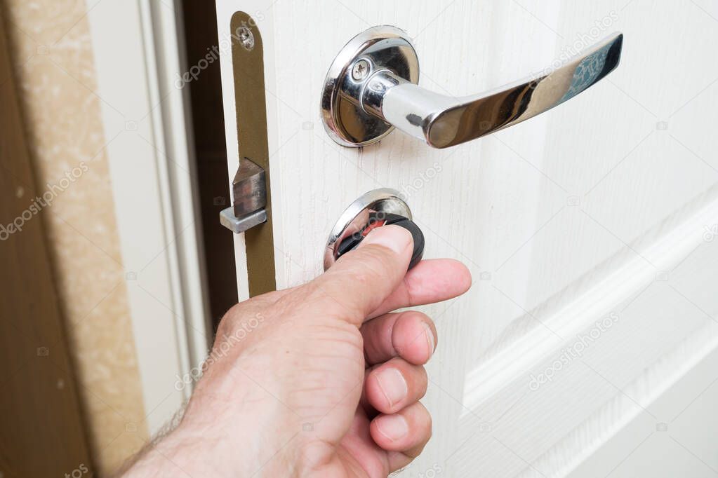 Worker installing or repairing new lock and door knob with screwdriver. Locksmith repair or install the door lock in house.