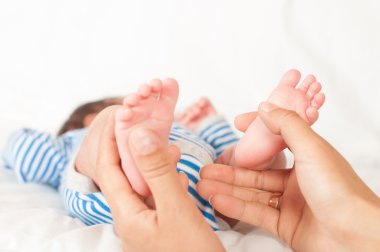 Annenin elleri ayakları bebeği tutmak.
