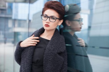 Kısa saçlı ve gözlüklü şehirde yürüyüş ile güzel genç kadın