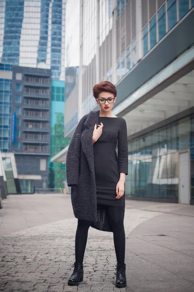 Beautiful young woman with short hair and glasses walking in the city — Stock Photo, Image