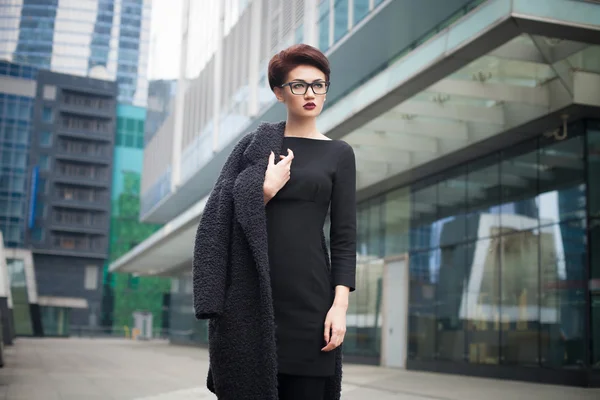 Beautiful young woman with short hair and glasses walking in the city — Stock Photo, Image