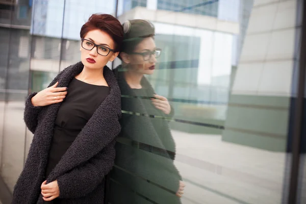 Beautiful young woman with short hair and glasses walking in the city — Stock Photo, Image