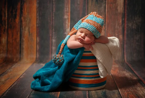 Linda menina recém-nascida dormindo com chapéu de malha em um fundo de madeira — Fotografia de Stock