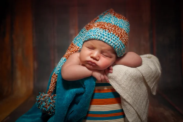 Bella neonata addormentata con cappello a maglia su uno sfondo di legno — Foto Stock