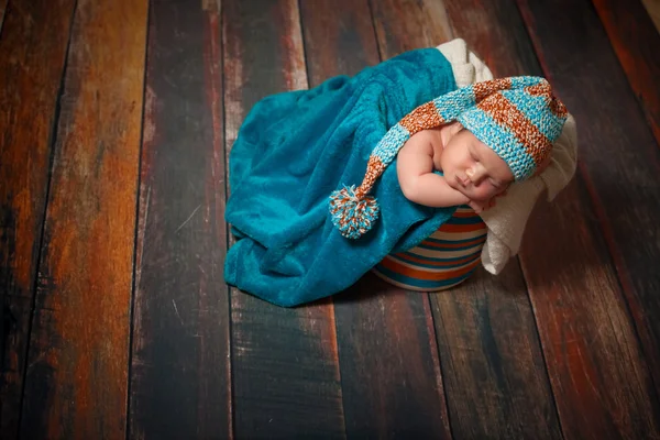 Mooie pasgeboren slapende babymeisje met gebreide muts op een houten achtergrond Rechtenvrije Stockafbeeldingen