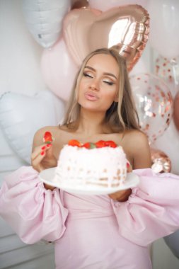 Güzel mutlu kız bir doğum günü pastasının üzerindeki mumu üfle