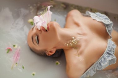 Çiçek banyosunda genç ve çekici bir kadın.