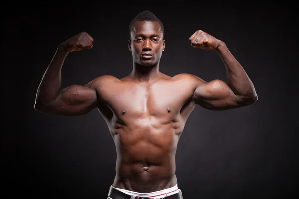 Beautiful and muscular black man in dark background — Stock Photo, Image