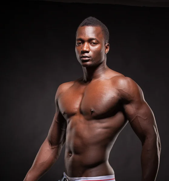 Beautiful and muscular black man in dark background — Stock Photo, Image