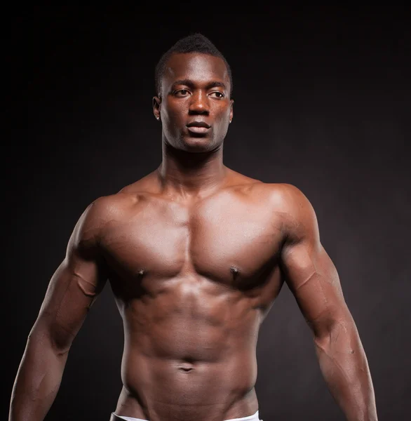 Beautiful and muscular black man in dark background — Stock Photo, Image