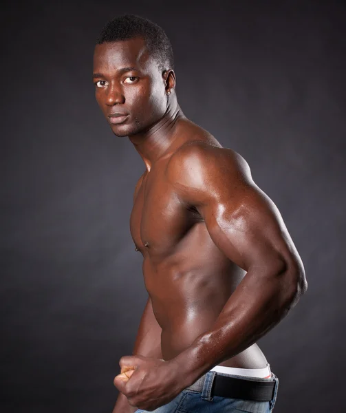 Beautiful and muscular black man in dark background — Stock Photo, Image