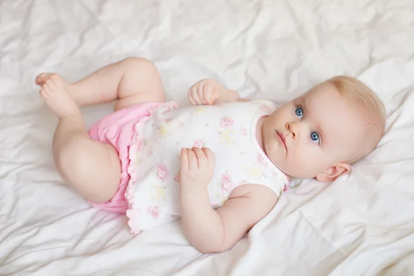 Beautiful baby girl lying on white bed — Stock Photo, Image