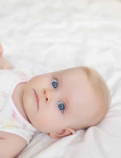 Beautiful baby girl lying on white bed — Stock Photo, Image
