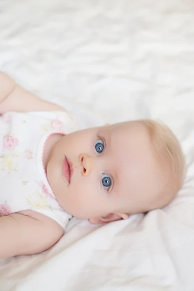 Beautiful baby girl lying on white bed — Stock Photo, Image