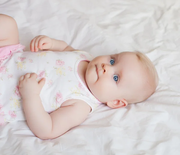 Beautiful baby girl lying on white bed — Stock Photo, Image