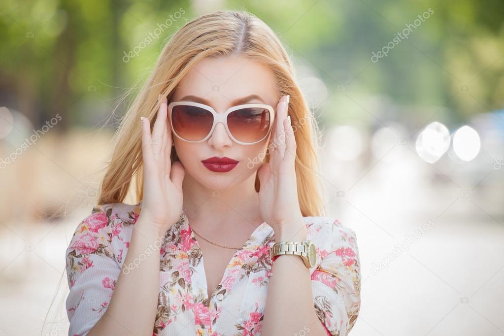 Beautiful  and fashion blonde young woman with sunglasses walking in the city. Summer photo