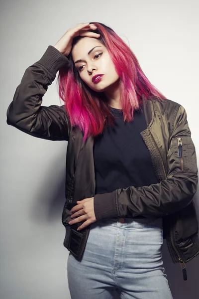 Jeune femme en veste et jeans bleus avec des cheveux roses studio tourné — Photo