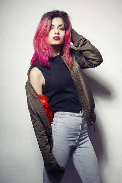 Jovem mulher de jaqueta e jeans azul com rosa estúdio de cabelo tiro — Fotografia de Stock