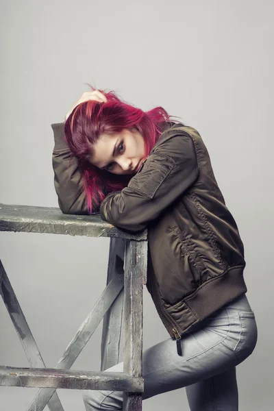 Jovem mulher de jaqueta e jeans azul com rosa estúdio de cabelo tiro — Fotografia de Stock