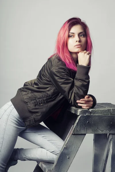 Jeune femme en veste et jeans bleus avec des cheveux roses studio tourné — Photo