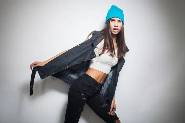Hipster meisje in gescheurde spijkerbroek, denim vest en blauwe hoed — Stockfoto