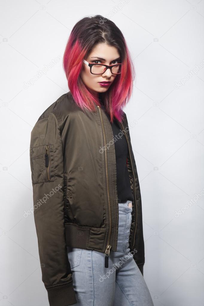 young woman in jacket and blue jeans with pink hair studio shot