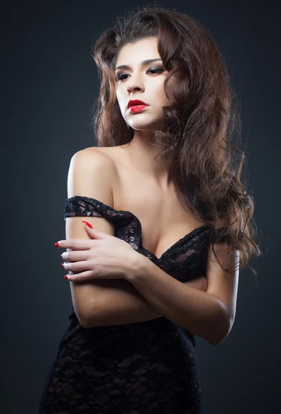 Mooie natuurlijke brunette krulhaar, portret van een jong meisje met rode lippen geïsoleerd op donker — Stockfoto