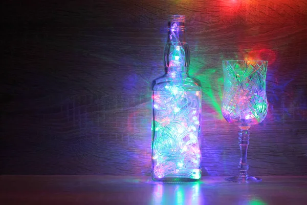 Copas Botellas Vidrio Con Guirnaldas Eléctricas Navideñas Sobre Fondo Madera — Foto de Stock