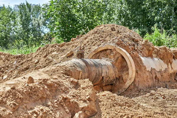 Реконструкция сети водоснабжения. Из грунта выкопали старую водопроводную трубу в железобетонном рукаве — стоковое фото