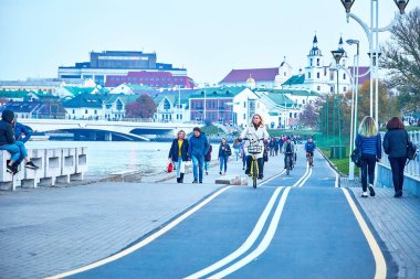 19 Ekim 2019 Minsk Belarus Bisiklet süren ve nehir kıyısında yürüyen insanlar iki kız beton levhaların üzerinde otururken